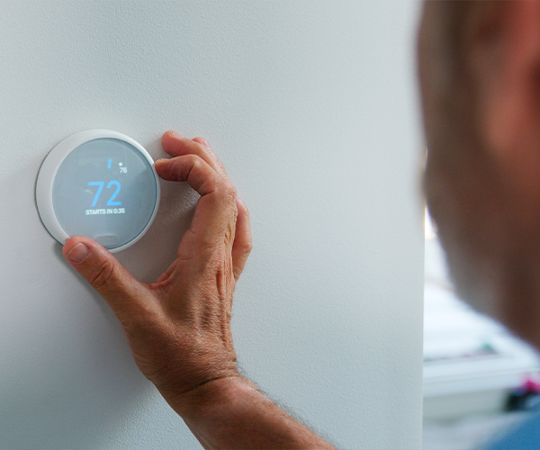 Una mujer ajusta su termostato inteligente para ahorrar energía